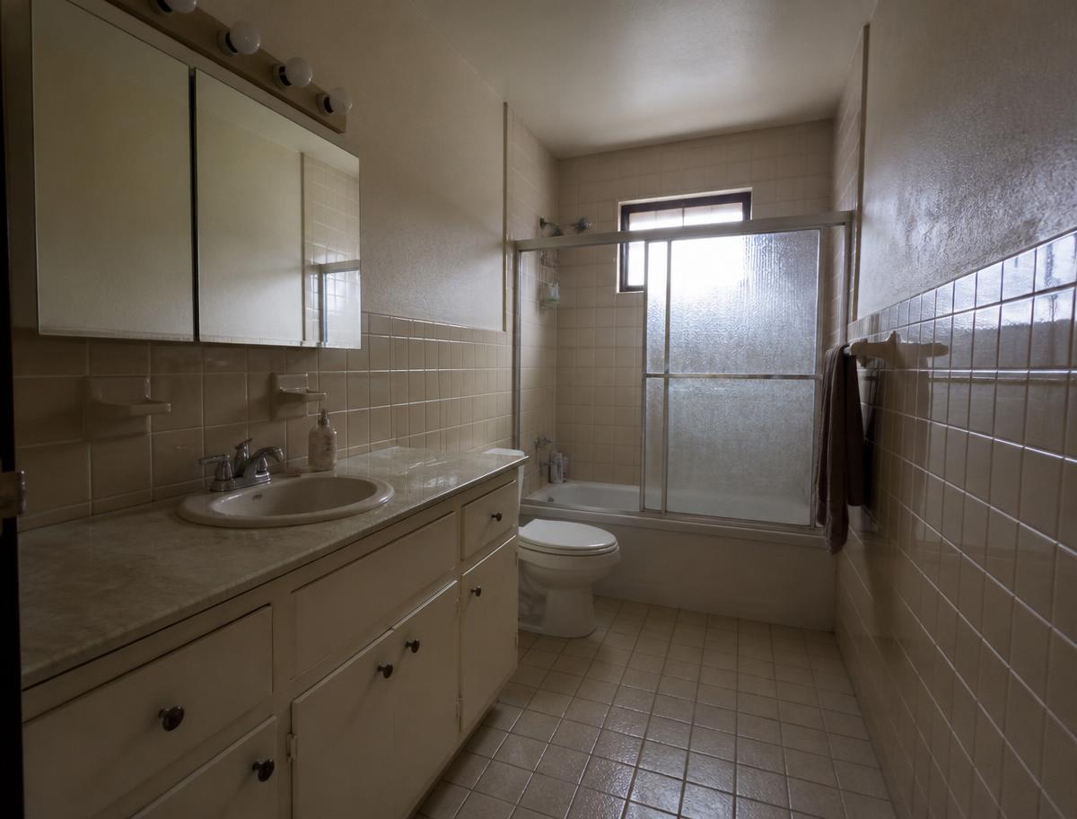 Dated bathroom before renovation with beige tile and an old vanity